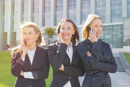 Three corporate business women standing and talking on the cellphoneの写真素材