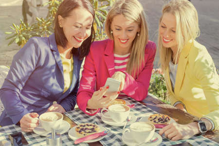 Woman showing pictures to her friends on mobile phoneの写真素材
