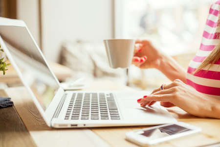 Woman drinking coffee and using laptop