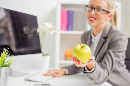 Business woman in office holding appleの写真素材