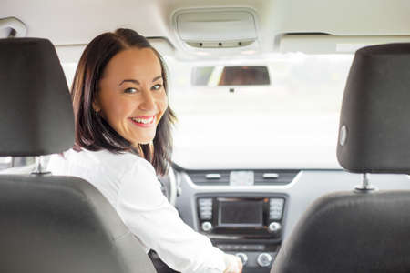 Woman looking back from drivers seatの写真素材