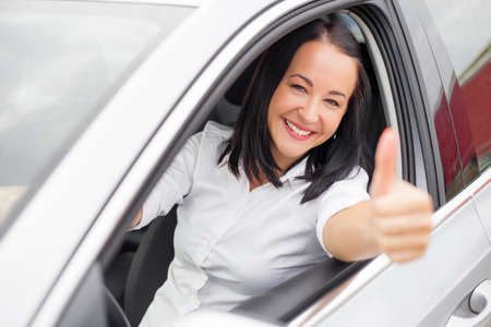 Woman sitting in the car and showing thumbs upの写真素材