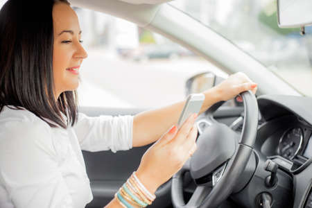 Female in car looking at her smart phoneの写真素材