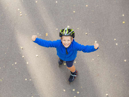 Happy boy on roller skates showing hands upの写真素材