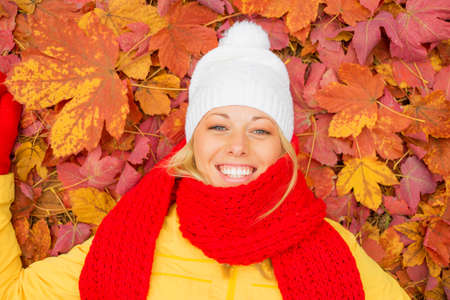 Happy woman laying in red leafsの写真素材