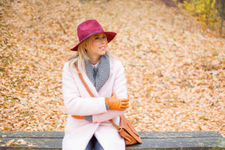 Fashionable woman sitting on the bench in parkの写真素材
