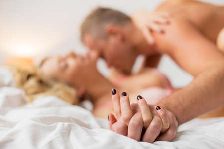 Man and woman holding hands while making loveの写真素材
