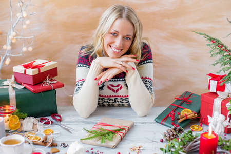 Happy woman sitting by the table and preparing giftsの写真素材