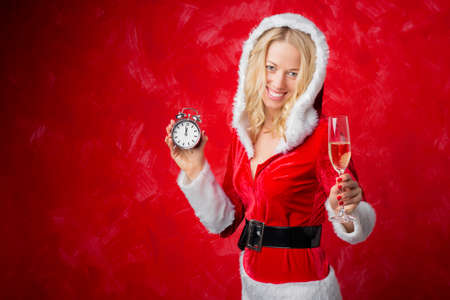 Woman in Santa costume holding clock and glass of campaignの写真素材