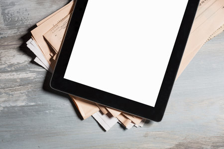 Tablet with blank screen and newspapers