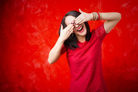 Happy woman covering her eyes with both handsの写真素材