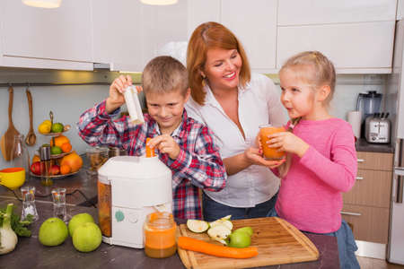Mother, son and daughter making fresh juice in kitchenの写真素材