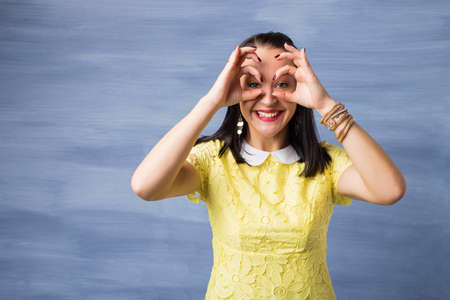 Woman looking through her hands and pretending to have binocularsの写真素材