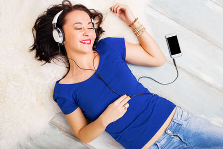 Woman laying on the ground and listening musicの写真素材