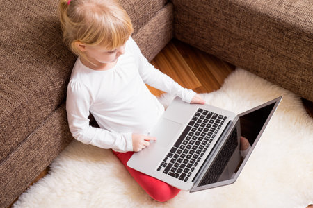 Child sitting on the ground with laptop in her lap