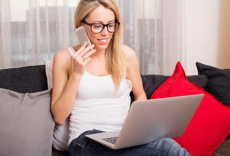 Woman talking on the phone and looking at laptopの写真素材