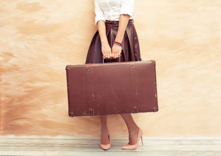 Woman holding antique suitcase for travelingの写真素材