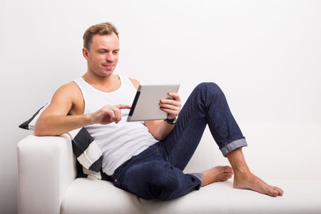 Man relaxing on couch and using tabletの写真素材