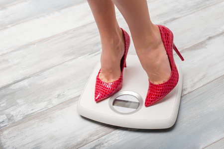 Woman with red high heels on weight scaleの写真素材