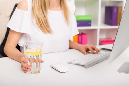 Woman drinking water while working at the officeの写真素材