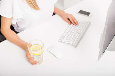 Woman having lemon water while workingの写真素材