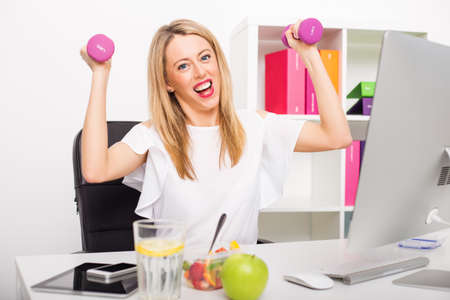 Happy woman in office being activeの写真素材