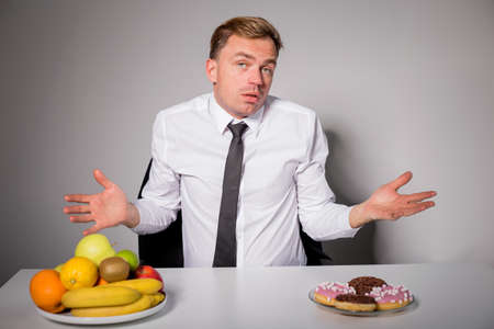 Man choosing between healthy and unhealthy foodの写真素材
