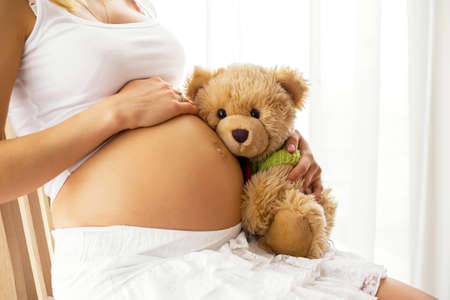 Pregnant woman holding teddy bearの写真素材