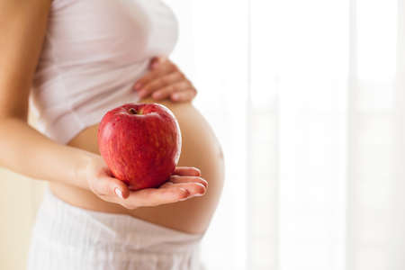 Pregnant woman holding apple in one handの写真素材
