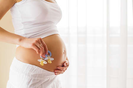 Pregnant woman holding baby pacifierの写真素材