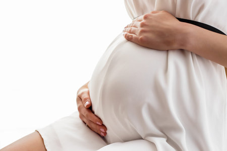 Pregnant woman in white dress sittingの写真素材