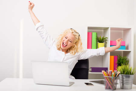 Business woman at the office celebrating with both hands upの写真素材