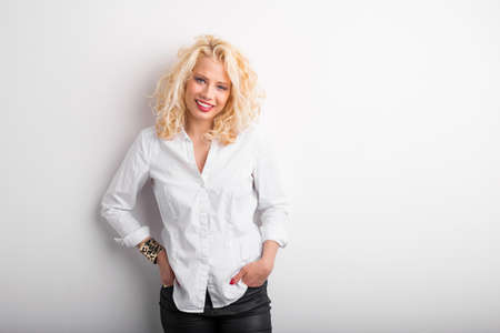 Shy woman leaning against white wallの写真素材