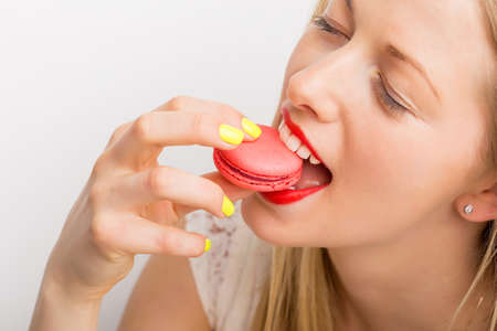 Happy woman eating pink macaroonの写真素材