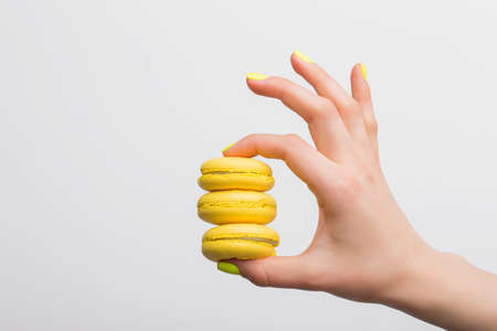 Person holding three yellow macaroonsの写真素材