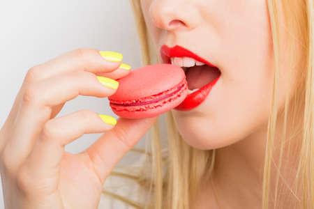 Woman eating red macaroonの写真素材