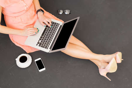 Modern female having coffee and using computerの写真素材