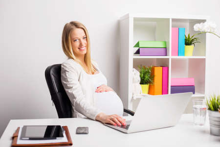 Happy pregnant woman working in the officeの写真素材