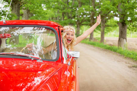 Happy and excited woman hanging out of vintage carの写真素材