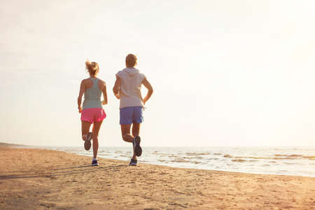 Two people running on the beachの写真素材