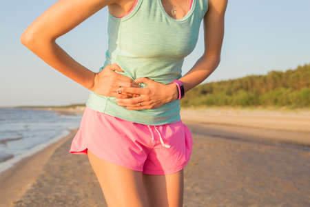 Woman runner having stomach crampsの写真素材