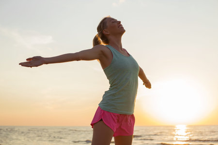 Happy and fit woman meditating on the beach