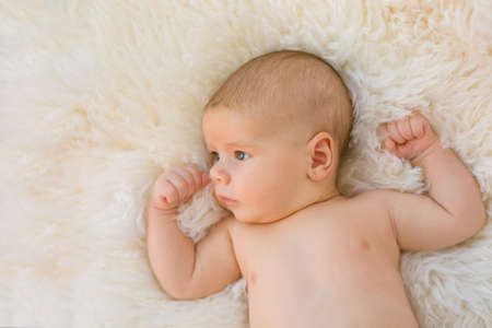 Baby boy sleeping on white furry backgroundの写真素材