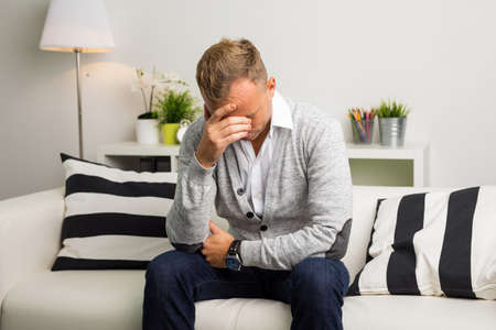 Depressed man sitting on the couchの写真素材