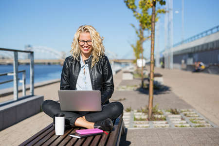 Woman sitting outside with laptop in her lapの写真素材