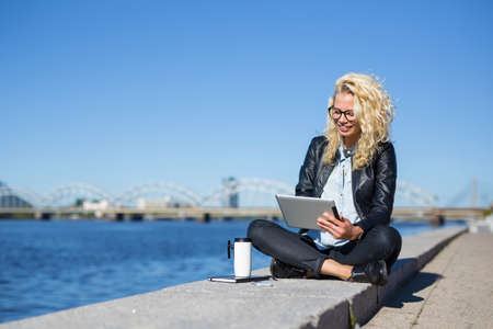 Woman working on tablet computer outdoorsの写真素材