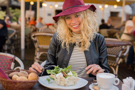 Beautiful woman sitting at cafe and eating saladの写真素材