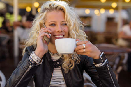 Woman drinking coffee and talking on mobile phoneの写真素材