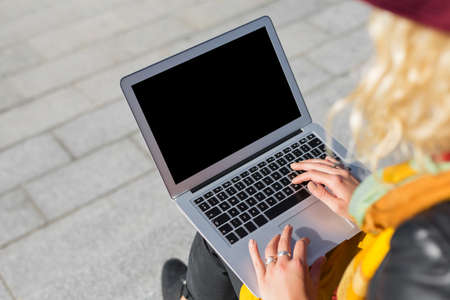 Woman sitting outside and using laptop computerの写真素材