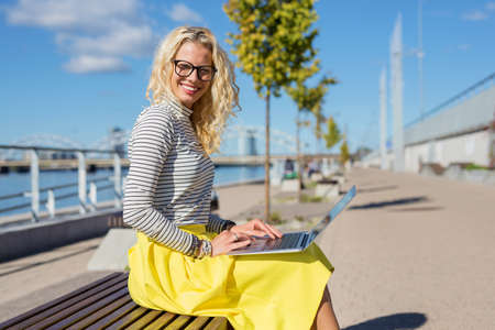 Stylish woman sitting ouside and working on laptopの写真素材